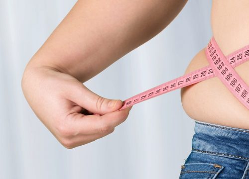 Man dealing with obesity measuring his waistline