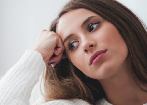 Woman in a white sweater looking sad