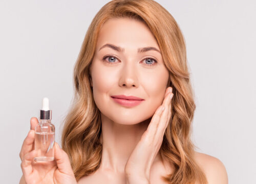 Woman holding serum bottle after using skincare products