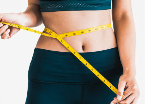 Woman with measuring tape around her waist after losing weight on our medical weight loss program